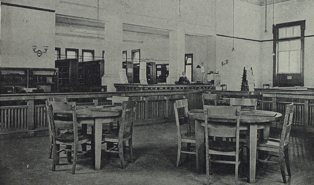 inside of library showing empty tables and large desk 
